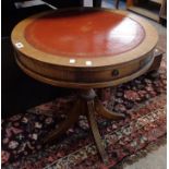 A 24" diameter reproduction mahogany drum table with red leather inset top, set on turned pillar and