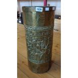 A brass umbrella stand with embossed carousing scene