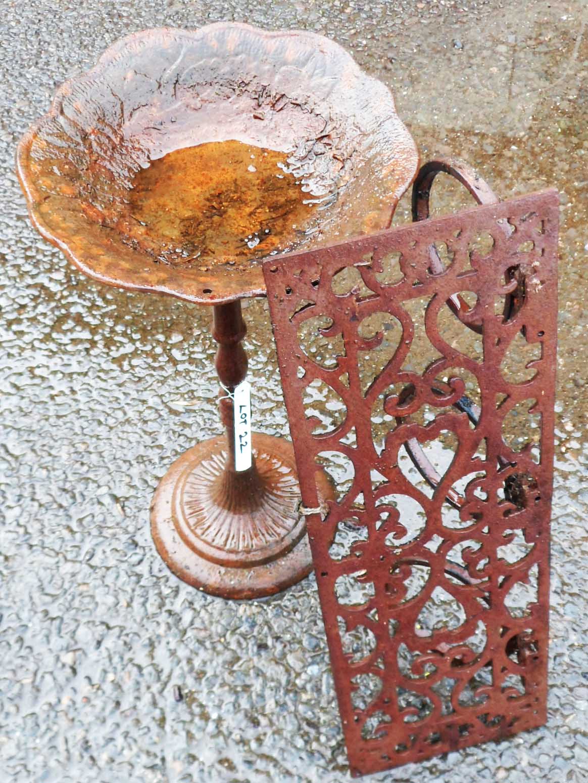 A cast metal bird bath and wrought iron garden shelf