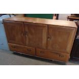 A 4' 3" vintage Ercol light elm sideboard with three cupboard doors and two short drawers under