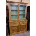 A 4' 19th Century waxed pine two part dresser with plate shelves enclosed by a pair of glazed