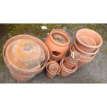 A collection of terracotta plant pots, one with lid, and a strawberry pot