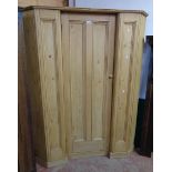 A 4' 9" waxed pine corner hall wardrobe with canted sides, decorative panelling and break front