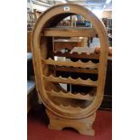 A 25" waxed mixed wood twenty two bottle wine rack of oval form, set on keg stand style base