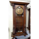 A walnut cased Vienna regulator style wall clock with printed dial, visible pendulum and twin weight