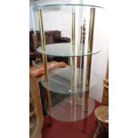 A 30" diameter late 20th Century display stand with four plate glass surfaces and brassed pillar