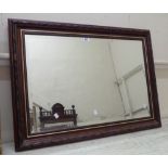 A decorative lacquered framed bevelled oblong wall mirror