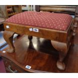 An early 20th Century walnut footstool with upholstered drop-in top, set on heavy cabriole legs with