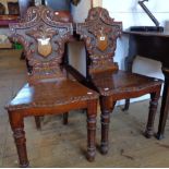 A pair of 19th Century carved oak hall chairs with ornate acanthus scroll shield backs and decorated