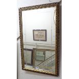 A gilt framed oblong wall mirror with decorative pierced border and engraved border to plate