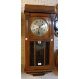 A vintage walnut cased wall clock with visible pendulum and eight day gong striking movement