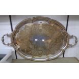 A 24 1/2" silver plated serving tray with ornate flanking cast handles and engraved decoration