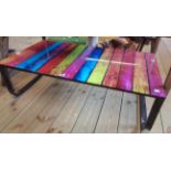 A 3' 5 1/4" modern black painted metal framed coffee table with brightly coloured printed plank