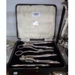 A case containing a pair of silver plated nut crackers, pair of picks and associated grape scissors