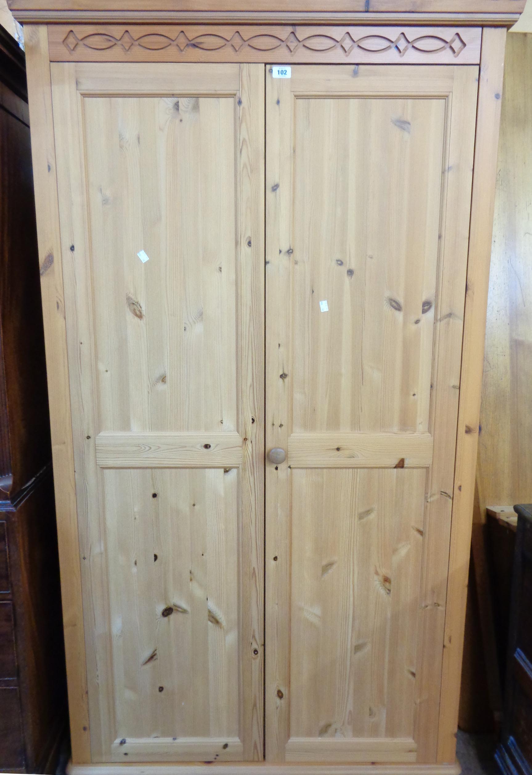 A 3' 6" modern pine double wardrobe with moulded decoration, hanging space and shelf enclosed by