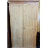 A 3' 6" modern pine double wardrobe with moulded decoration, hanging space and shelf enclosed by