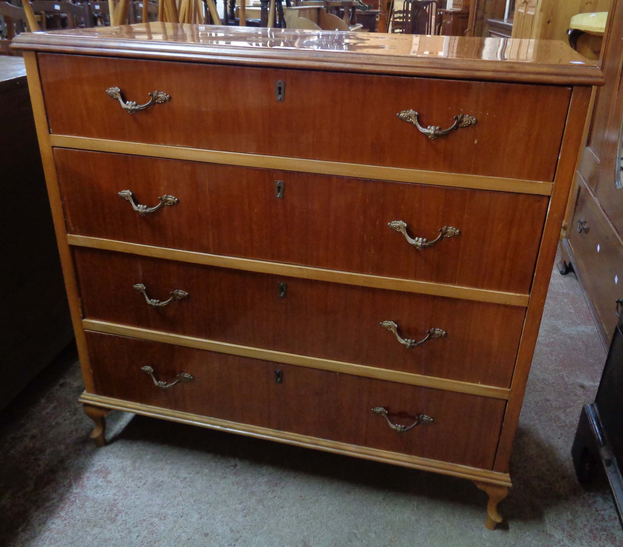 A 3' 4" highly polished mixed wood chest of four long graduated drawers, set on short cabriole legs