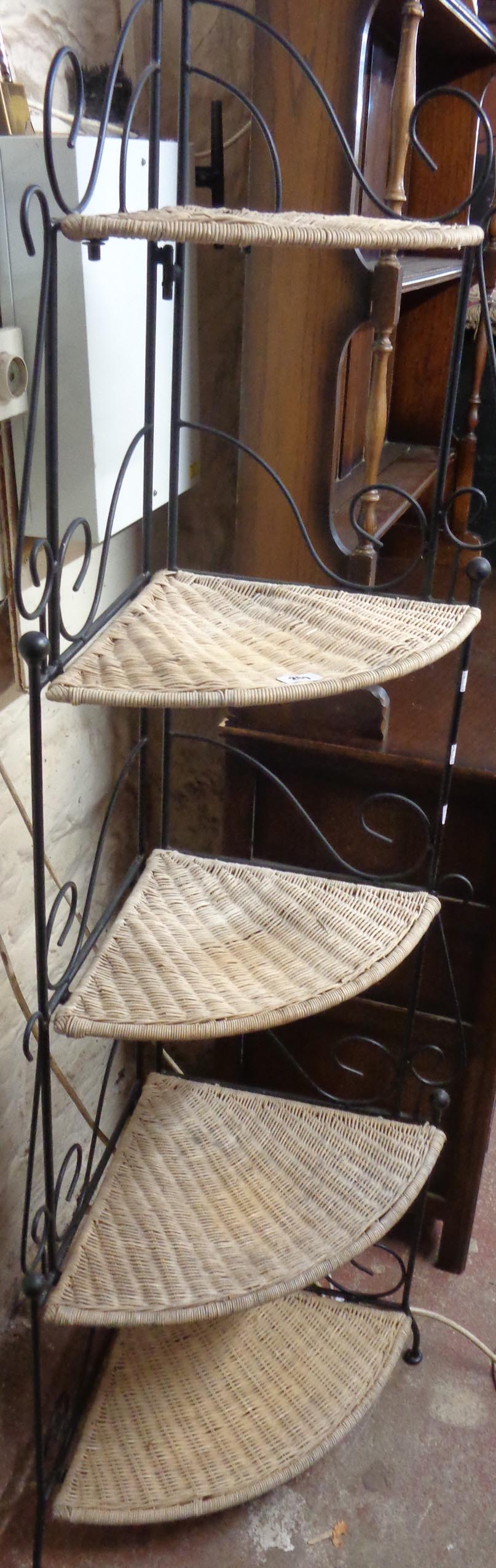A 24" black painted wrought metal corner stand with five graduated wicker surfaces