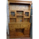 A 4' late 20th Century polished pine two-part dresser with shelves and flanking glazed panel doors