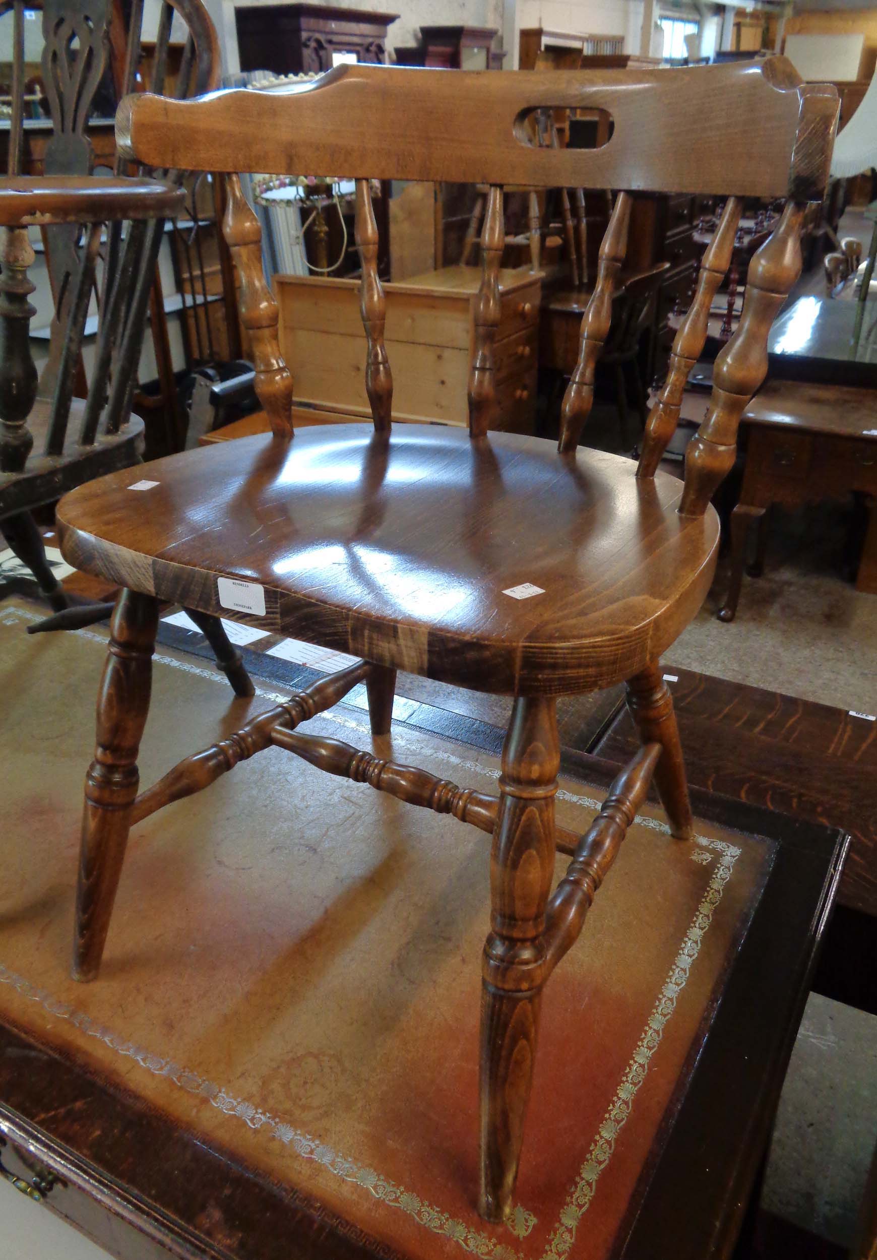 A 20th Century stained mixed wood spindle back bow elbow chair with solid sectional seat and