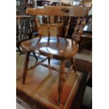 A 20th Century stained mixed wood spindle back bow elbow chair with solid sectional seat and