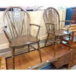 A pair of 20th Century stained wood wheel back elbow chairs with solid sectional seats, set on