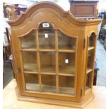 A 26 1/2" modern polished oak wall mounted collector's cabinet with canted sides, glazed door and