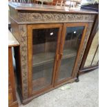 A 36" early 20th Century oak book cabinet with carved decoration and adjustable shelves enclosed