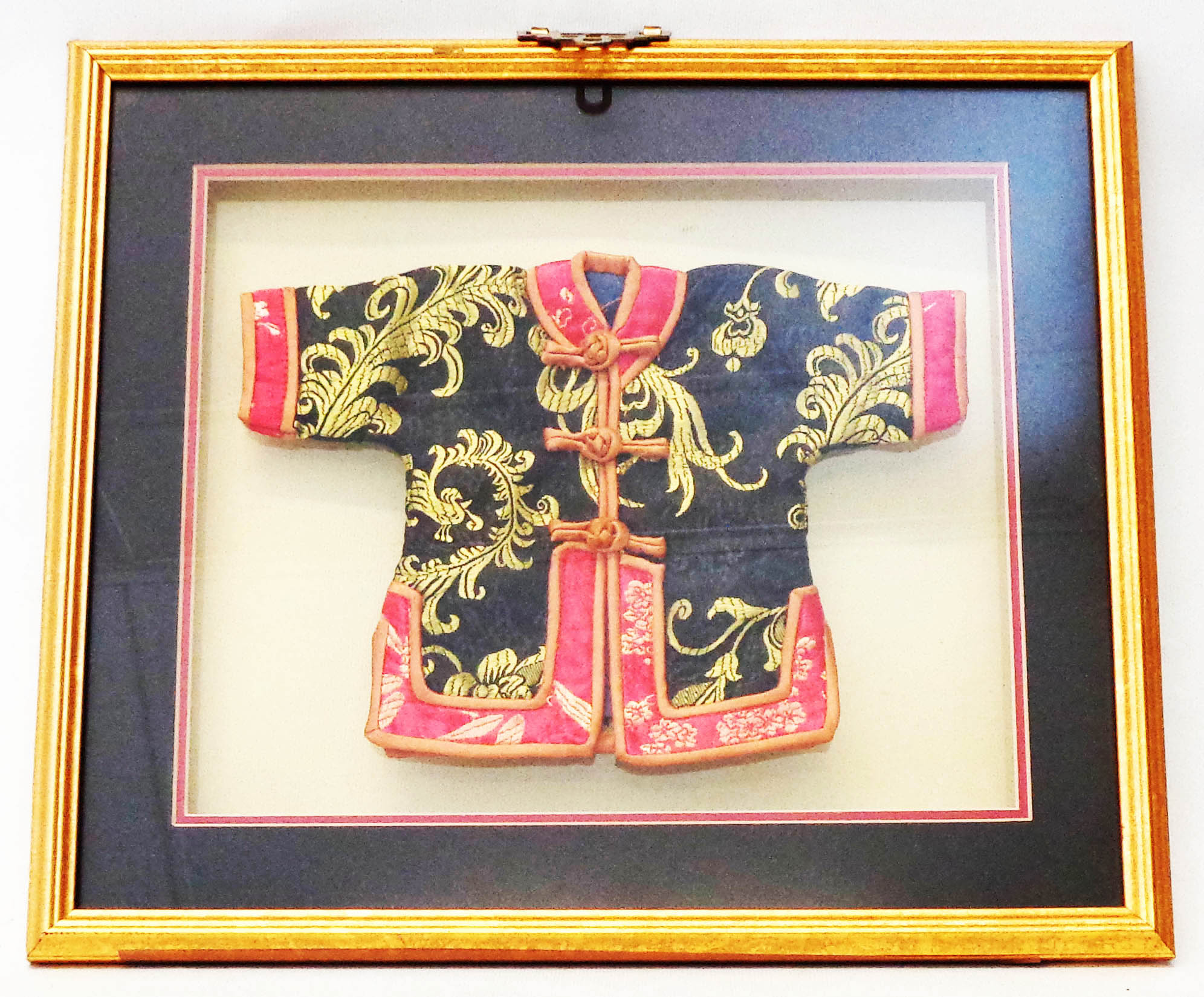 A box framed Chinese doll's jacket with ornate embroidered decoration