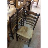 A set of four elm framed ladder back dining chairs with woven rush seats, set on turned front