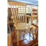 A modern blonde wood high lath back kitchen elbow chair with solid sectional seat, set on turned