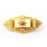 A cased Victorian marked 15ct. yellow metal panel brooch, set with central garnet within a rose