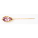 A Victorian yellow and rose metal stick pin set with large drop shaped amethyst
