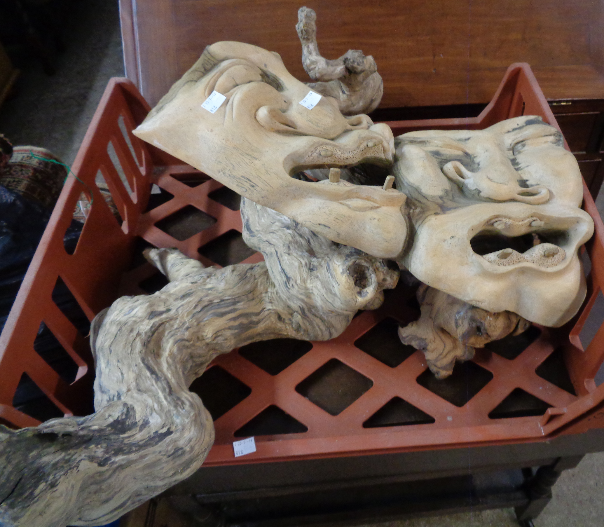 A driftwood carving of grotesque masks and two further pieces of driftwood