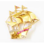 A 1 1/2" unmarked high carat yellow metal galleon pattern brooch, set with paved row of rubies,