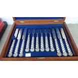 A mahogany cased set of twelve each silver plated fruit knives and forks with ornate twist handles