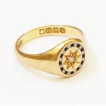 An 18ct. gold ring, with gypsy set central diamond within a black and white enamelled border