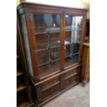 A 3' 6 1/2" Old Charm stained oak display cabinet with glass shelves enclosed by a pair of leaded
