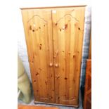 A 34" modern polished pine wardrobe with hanging space and shelf enclosed by a pair of moulded