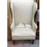 A 20th Century box framed wing back armchair upholstered in pale striped material, set on turned