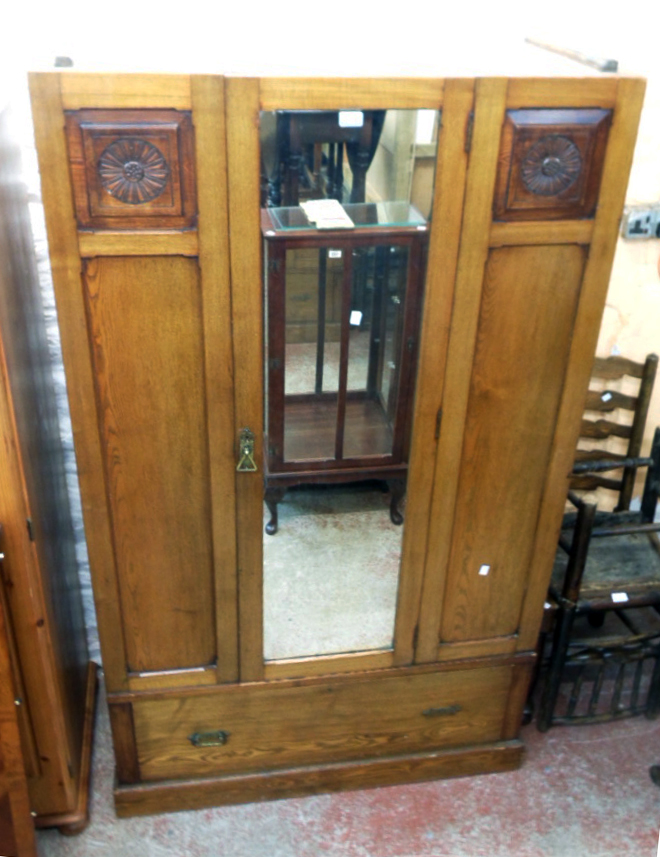 A 3' 7 1/2" early 20th Century stained oak wardrobe with hanging space enclosed by a mirror panel