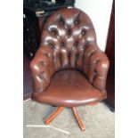 A 20th Century office swivel elbow chair upholstered in brown button back leather, set on a polished