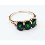 A hallmarked 375 gold ring, set with three oval green garnets and flanking tiny diamonds