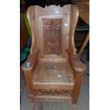 A stained pine child's wing back throne chair with decorative back panel and locker seat