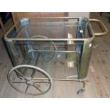 A vintage brass dinner wagon with spoked wheels and glass surfaces