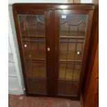 A 30" 1930's polished oak four shelf book cabinet enclosed by a pair of leaded glazed panel doors
