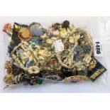 A bag containing a quantity of vintage costume jewellery including brooches, etc.