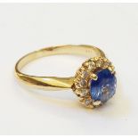 A hallmarked 585 gold ring, set with central sapphire within a diamond encrusted border