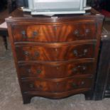 A 24" reproduction mahogany and cross banded serpentine front chest of four long drawers, set on
