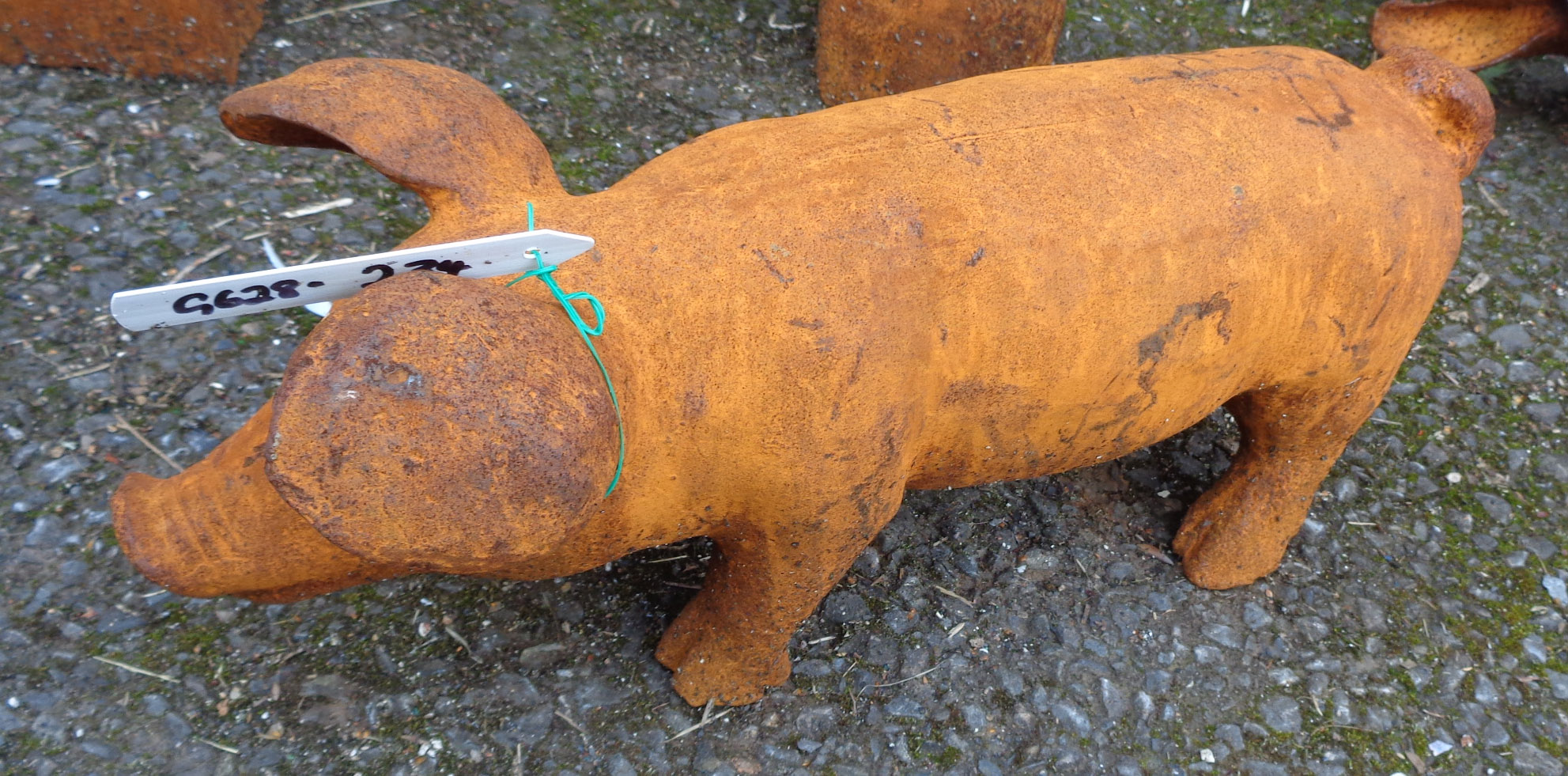 A cast iron garden pig with rusted finish